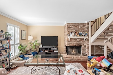 Living area featuring ornamental molding, a fireplace, wood finished floors, and stairway