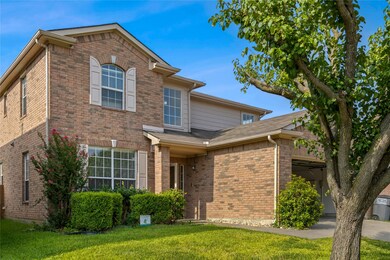 Traditional-style house with brick siding, a front yard, and an attached garage