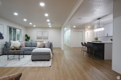 Living area with recessed lighting, light wood-type flooring, and a textured ceiling