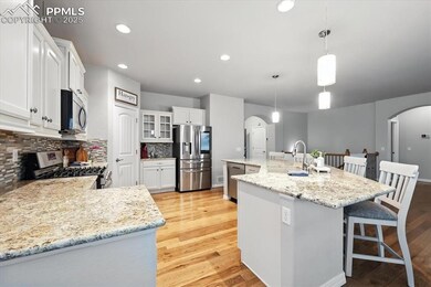 Kitchen featuring stainless steel appliances, arched walkways, tasteful backsplash, light wood-type flooring, and a breakfast bar area