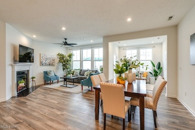 Dining space with ample room, view of glass-covered electric fireplace, recessed lighting, and wood-like finished plank floors