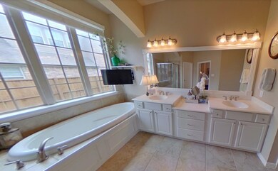 Full bathroom featuring a garden tub, double vanity, and a stall shower
