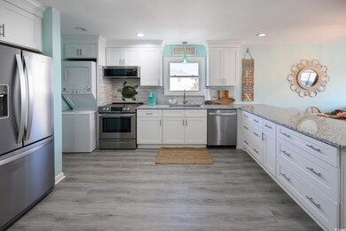 Kitchen with sink, white cabinets, stacked washer 