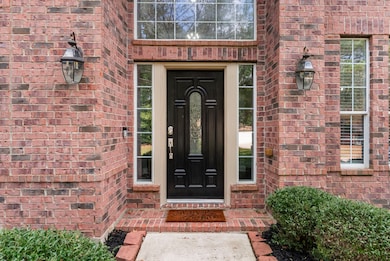 Charming coach lights and a rich wood door with stained glass detailing create a warm, elegant welcome at the front entrance.