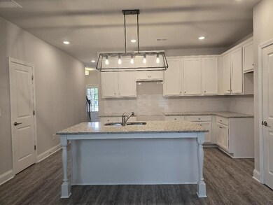 Kitchen featuring dark wood finished floors, a kitchen island with sink, white cabinetry, and recessed lighting