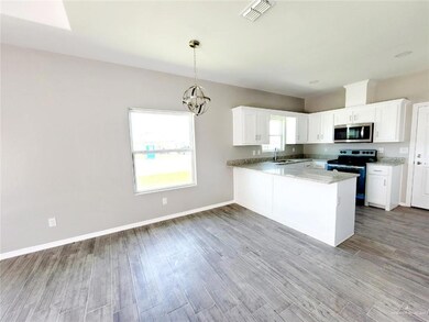 Kitchen featuring stainless steel microwave, electric range oven, light wood-style floors, a peninsula, and white cabinetry