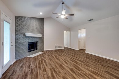 Unfurnished living room with brick wall, vaulted ceiling, dark hardwood / wood-style floors, a fireplace, and ceiling fan