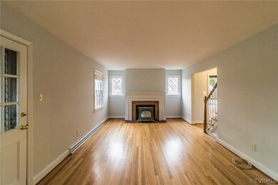 Spacious living room with hardwood floors and fireplace with wood stove.