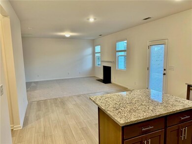 Kitchen with light stone countertops, a center island, a fireplace with flush hearth, light wood-style floors, and recessed lighting