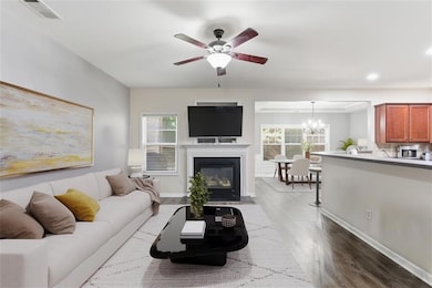 Living room featuring healthy amount of natural light, dark wood-style floors, ceiling fan, a fireplace with flush hearth, and recessed lighting