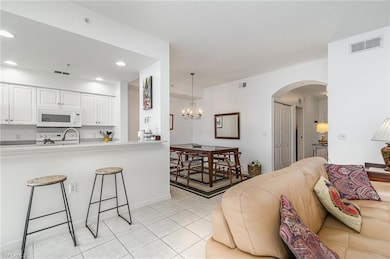 Living room with arched walkways, light tile patterned floors, a chandelier, recessed lighting, and baseboards