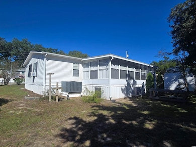 Back of property featuring a sunroom, a lawn, and a deck