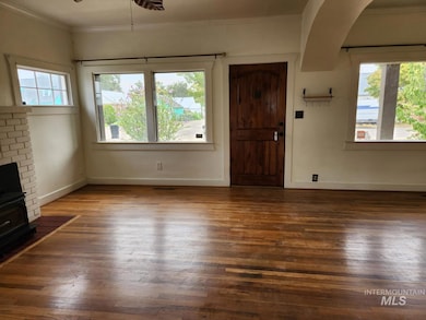 Entrance foyer with dark wood-type flooring, ornamental molding, ceiling fan, and a brick fireplace