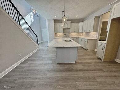 Kitchen with a chandelier, a kitchen island with sink, decorative light fixtures, Quartz countertops, and backsplash