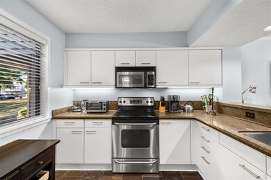 Kitchen featuring white cabinetry, sink, dark ston