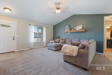 Carpeted living area featuring a ceiling fan and lofted ceiling