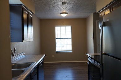 Kitchen with SS & black appliances, dark wood-type flooring, and light countertops