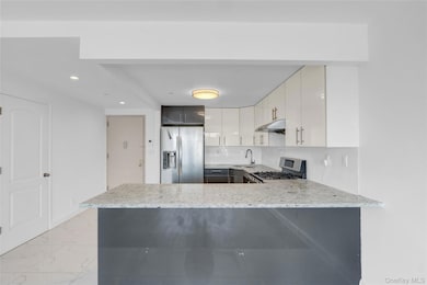 Kitchen featuring stainless steel appliances, tasteful backsplash, light stone counters, a peninsula, and recessed lighting