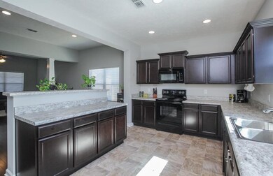 This kitchen is just what you want!  Beautifully stained wooden cabinets, black appliances, recessed lighting, and more!