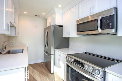 Kitchen featuring stainless steel appliances, white cabinets, recessed lighting, and light wood-type flooring