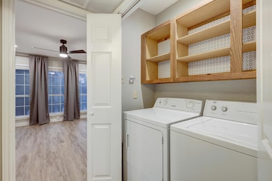 Laundry area featuring a ceiling fan, light wood finished floors, and washer and clothes dryer