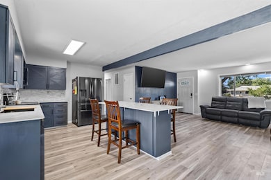 Kitchen with stainless steel fridge, a kitchen breakfast bar, open floor plan, light wood-style flooring, and backsplash
