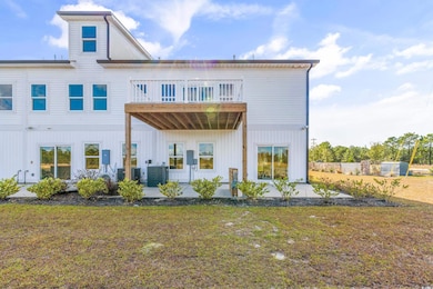 Back of house featuring a patio area, a lawn, a balcony, and board and batten siding
