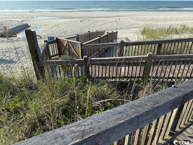 Wooden deck featuring view of water and beach