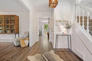 Foyer entrance featuring wood finished floors, crown molding, stairs, and a textured ceiling