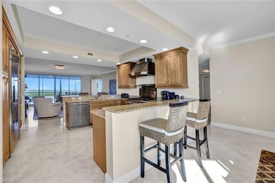 Kitchen with wall chimney exhaust hood, light ston