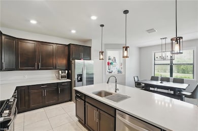 Kitchen featuring stainless steel appliances, a sink, light countertops, pendant lighting, and recessed lighting