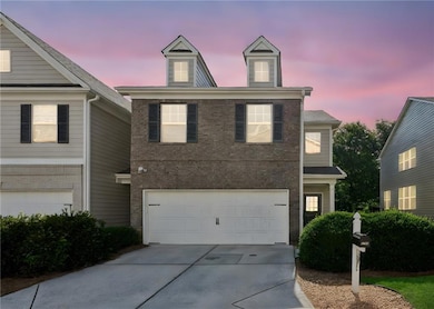 Traditional-style house featuring a garage, concrete driveway, and brick siding