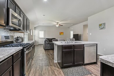 The kitchen island includes a sink and dishwasher,