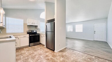 Kitchen with a textured ceiling, appliances with stainless steel finishes, light countertops, white cabinetry, and light tile patterned floors