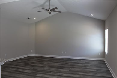 Spare room with dark wood-type flooring, ceiling fan, vaulted ceiling, and recessed lighting