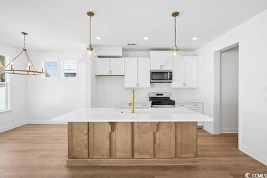 Kitchen featuring visible vents, white cabinetry, stainless steel appliances, light countertops, and a chandelier