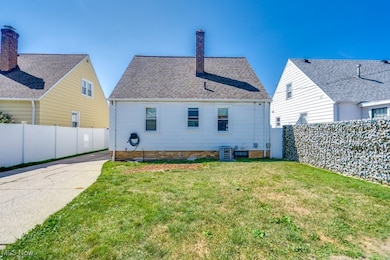 Rear view of property featuring a yard and central AC