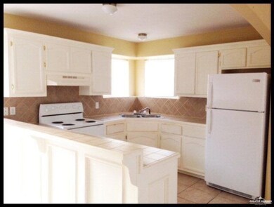 Kitchen with tile countertops, white appliances, and tasteful backsplash