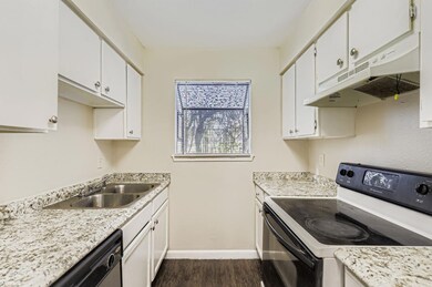 Kitchen with black range with electric stovetop, under cabinet range hood, white cabinetry, dishwasher, and dark wood-style floors