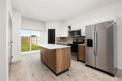 Kitchen featuring stainless steel appliances, white cabinetry, a kitchen island, light countertops, and tasteful backsplash