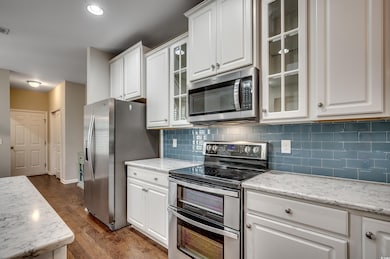 Kitchen with light stone countertops, tasteful bac