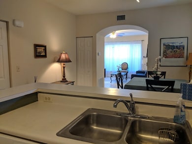 Kitchen with arched walkways, light countertops, ceiling fan, and open floor plan