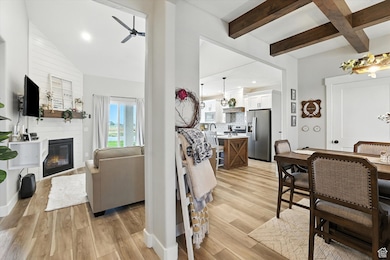 Living area with a ceiling fan, light wood finished floors, beam ceiling, a fireplace, and recessed lighting