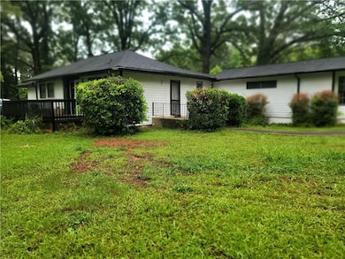 Back of house with a deck and a lawn