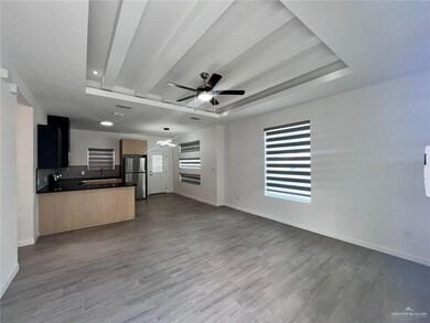 Unfurnished living room with a raised ceiling, ceiling fan, light hardwood / wood-style flooring, and sink