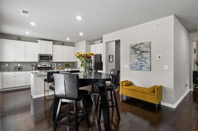 Kitchen featuring stainless steel appliances, granite countertops and kitchen island with sink, decorative backsplash,  and hardwood flooring