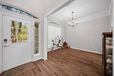 Entrance foyer with dark wood-style floors, a chandelier, healthy amount of natural light, and ornamental molding