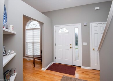 Open foyer with vaulted ceiling, coat closet, wood