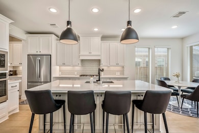 The kitchen boasts a deco wood paneled island with additional storage in the front of the island. Upgraded with built-in stainless steel appliances, a 5 burner gas cooktop, chic pendant lighting, and white cabinets, this kitchen is ideal for cooking for the whole family or hosting holidays!
