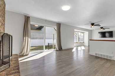 Unfurnished living room with a fireplace, wood finished floors, and a ceiling fan
